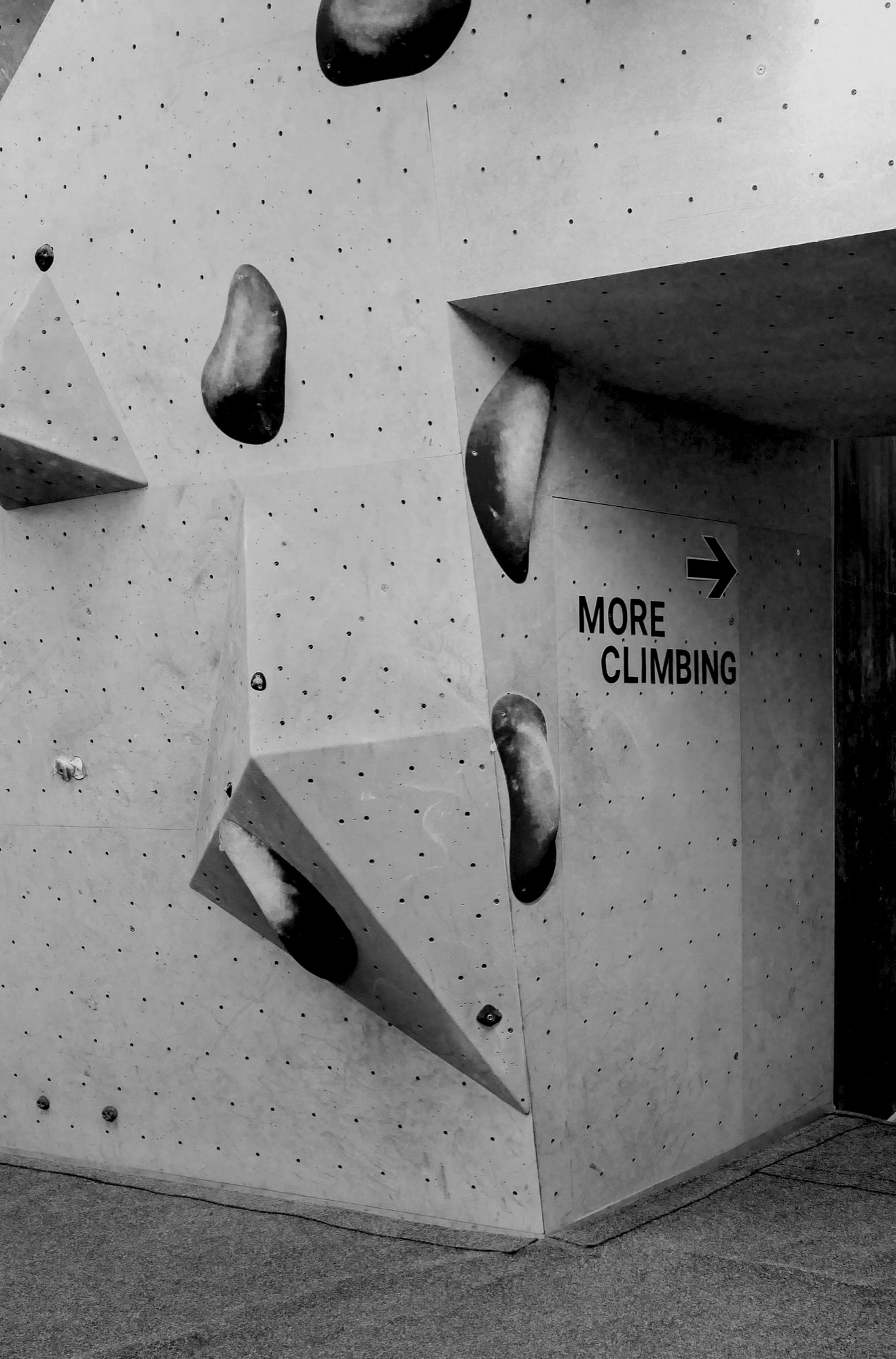 A bouldering wall with a sign reading More Climbing